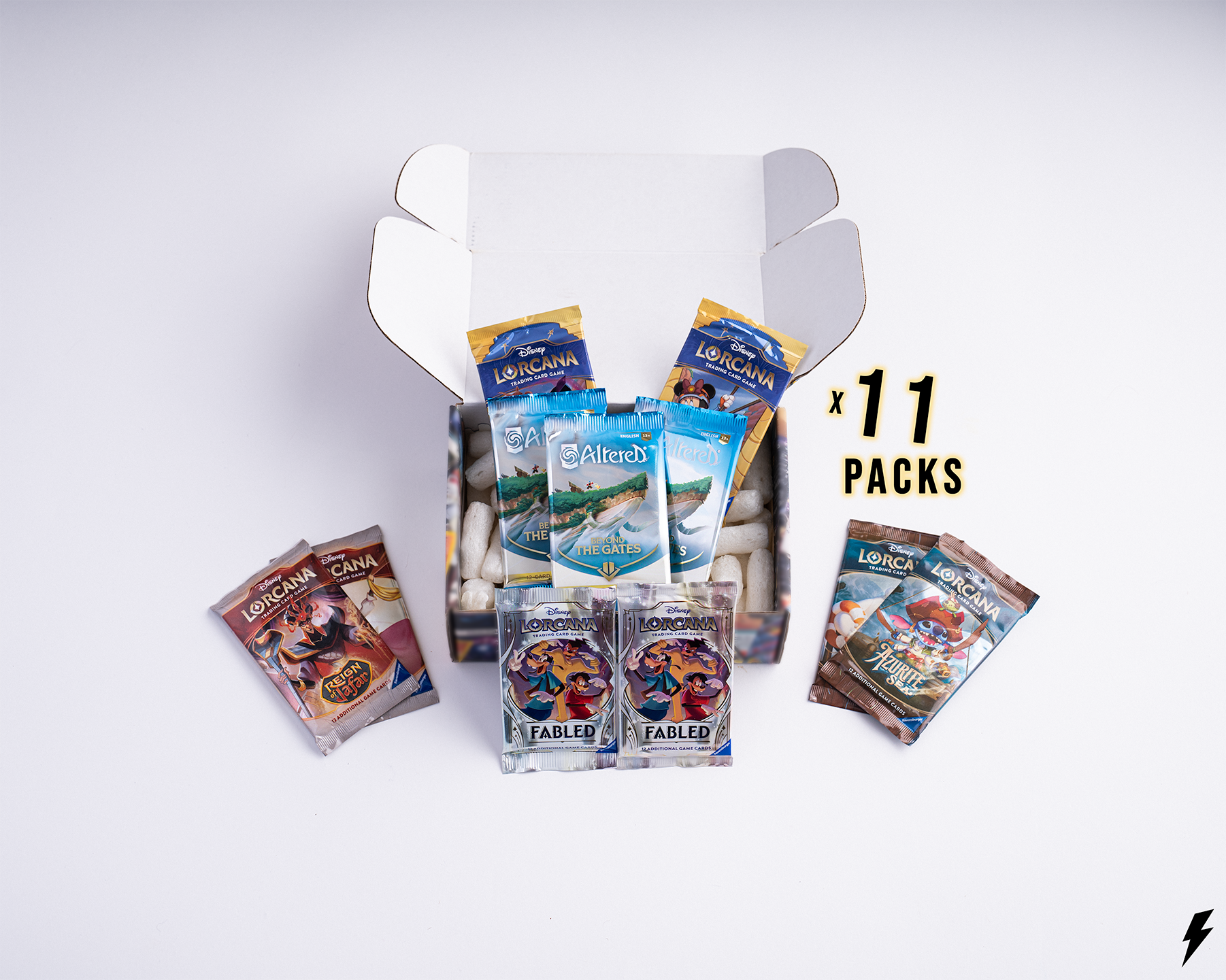 Open Booster Crate box containing 11 Disney Lorcana booster packs from various sets, shown with smaller side piles and “x 11 Packs” text on the right