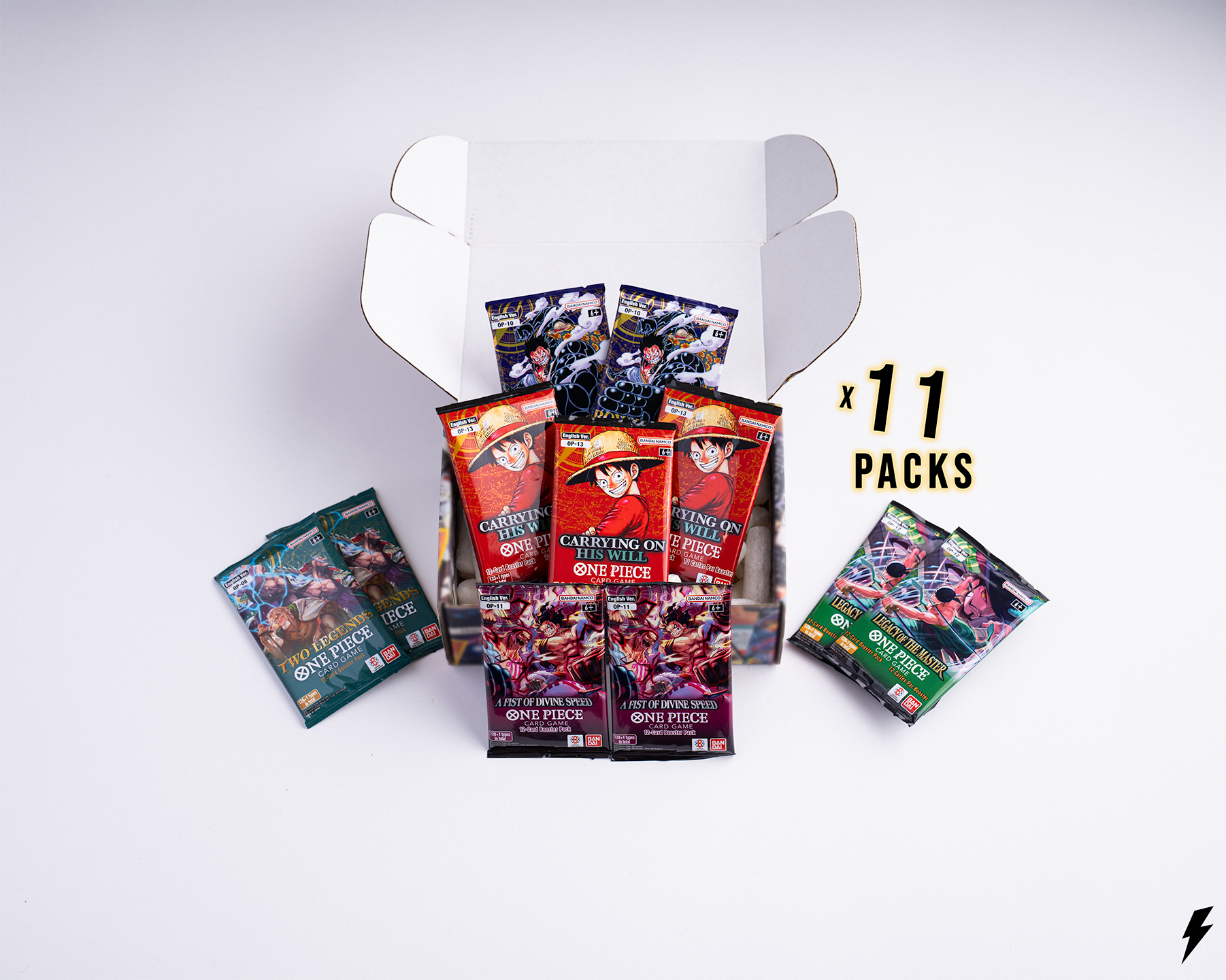Open Booster Crate box containing 11 One Piece booster packs from various sets, shown with two smaller side piles and “x 11 Packs” text on the right.